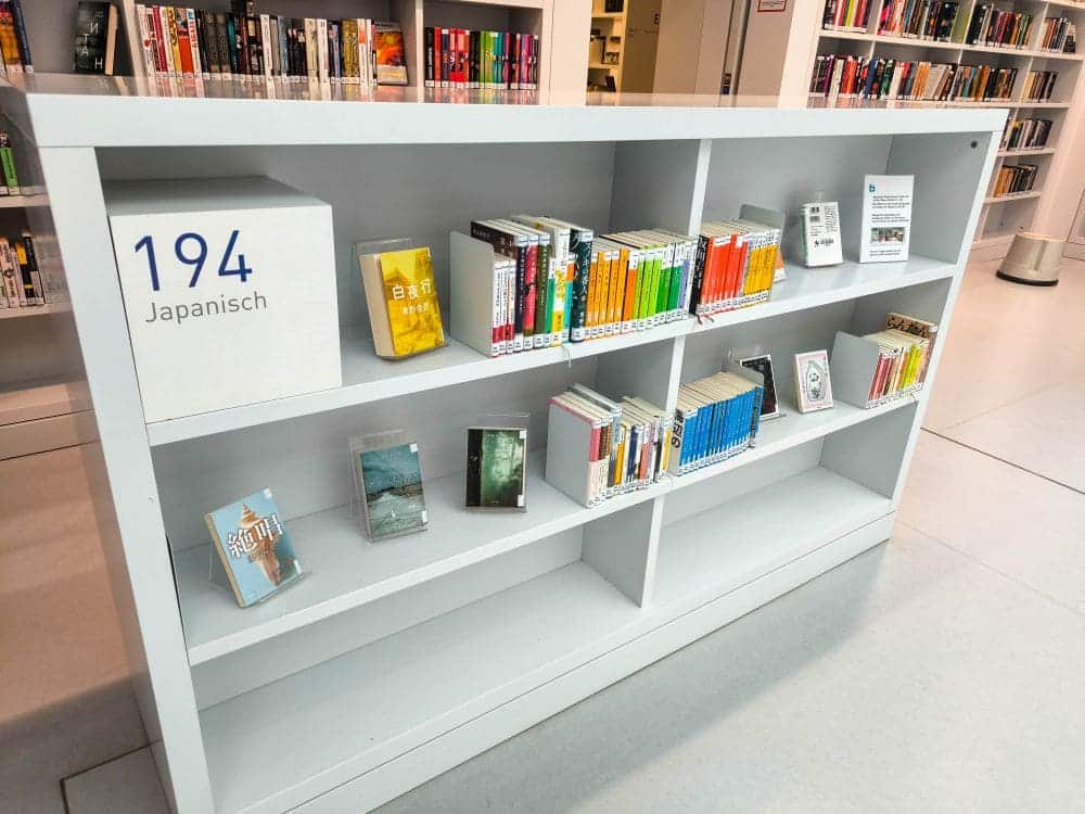 Das Bücherregal „194 Japanisch“ in der Bibliothek präsentiert eine Auswahl japanischer Bücher, übersichtlich angeordnet auf drei Regalen. Dieses einladende Paradies für Bücherliebhaber liegt eingebettet in die umfangreiche Sammlung der Stadtbibliothek Stuttgart und bietet eine gut organisierte Oase für Leser.