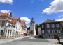 Im Herzen von Zella-Mehlis gelegen, bezaubert diese malerische Kleinstadtstraße mit ihrer traditionellen europäischen Architektur und dem historischen Kirchturm in der Mitte. Die malerischen Gebäude bestechen durch ihre roten Ziegeldächer vor dem Hintergrund eines blauen Himmels mit zarten, vereinzelten Wolken.