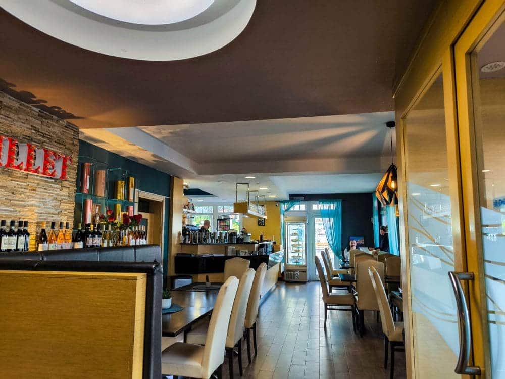 Ein modernes Restaurant im Ostseebad mit beigen Stühlen, Holzboden, einer gut ausgestatteten Bar und großen Fenstern, die viel Tageslicht hereinlassen. Die gemütliche Atmosphäre macht es perfekt für einen entspannten Urlaub in Rerik.