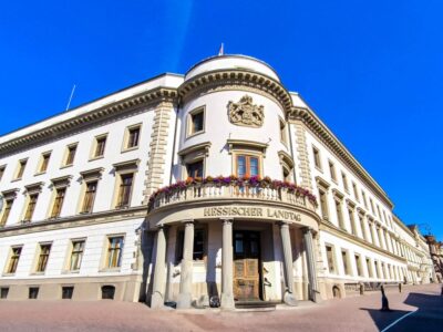 In der Hessischen Landeshauptstadt steht der Hessische Landtag, ein historisches weißes Gebäude mit kunstvollen Details und Bogenfenstern, mit blumengeschmücktem Balkon und blauem Himmel - ein Muss, wenn Sie Wiesbaden entdecken.