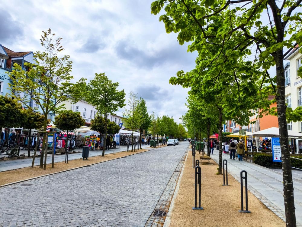 Eine Straße in Kühlungsborn mit Bäumen und Spaziergängern, perfekt für eine entspannte Auszeit an der Ostsee.