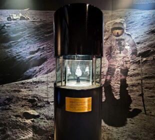 Ein Mondgestein in einer Glasvitrine des Rieskratermuseums mit einem Astronauten auf der Mondoberfläche und einem Lunar Rover in der Ferne verdeutlicht die einzigartige Verbindung Nördlingens zur geologischen Geschichte der Schwäbischen Alb.