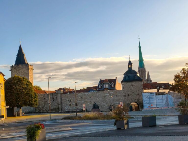 Mühlhausen: Stadtmauer, Kirchen und Müntzer-Geschichte in der Stadt der Türme 1 Die historische Stadtmauer aus Stein in Mühlhausen mit Türmen und einem Kirchturm unter strahlend blauem Himmel.